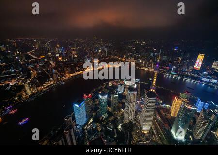 Blick aus der Vogelperspektive über den Bund, den Huangpu Fluss und das Finanzviertel Lujiazui mit beleuchteten Wolkenkratzern in Pudong in der Stadt Shanghai bei Nacht, China Stockfoto