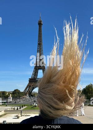 Blick vom Trocadéro auf die blonden Haare der Frau, die im Wind weht, mit dem Eiffelturm als Hintergrund, wunderschöner Herbsttag im September 2025. Stockfoto