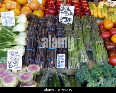 SEATTLE - 23. APR 2025 - farbenfrohe Auswahl an frischem lila Spargel, grünen Produkten und lebendigen Früchten, die auf dem lokalen Bauernmarkt kunstvoll zubereitet werden Stockfoto