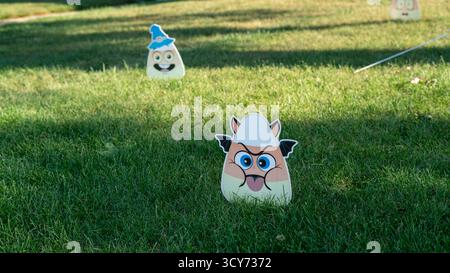 Niedliche Bonbonkorn Halloween-Dekorationen mit lächelnden Gesichtern sitzen fröhlich in einem grasbewachsenen Vorgarten und verleihen der saisonalen Outdoor-Dekoration eine verspielte Note. Stockfoto