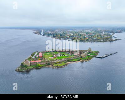 Breiter Panoramablick auf die Insel der Festung Oreshek im Zentrum, mit dem Wasser und der fernen Stadt im Hintergrund Stockfoto