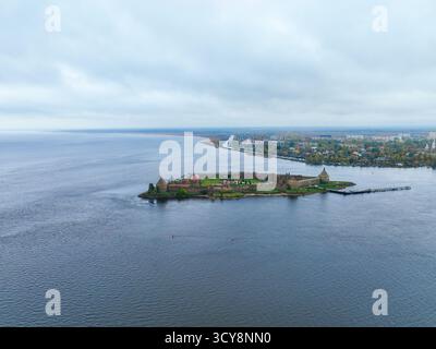 Aus der Ferne die Insel der Festung Oreshek, die sich in der weiten Weite des Flusses oder Sees unter einem bewölkten Himmel befindet Stockfoto
