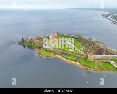 Breiter Panoramablick auf die Insel der Festung Oreshek im Zentrum, mit dem Wasser und der fernen Stadt im Hintergrund Stockfoto