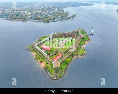 Breiter Panoramablick auf die Insel der Festung Oreshek im Zentrum, mit dem Wasser und der fernen Stadt im Hintergrund Stockfoto
