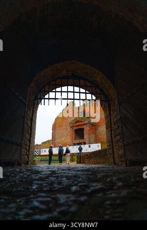 Shlisselburg, Russland - 13. Mai 2024: Vier Touristen, Kaukasier verschiedener Altersgruppen, stehen im dunklen Haupttor der Festung Oreshek mit Blick auf die Festung Stockfoto