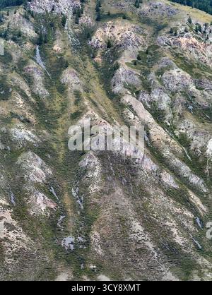 Zerklüftete Berglandschaft mit steilen Hängen, die mit verstreutem Grün bedeckt sind. Berglandschaft im natürlichen Hintergrund. Stockfoto