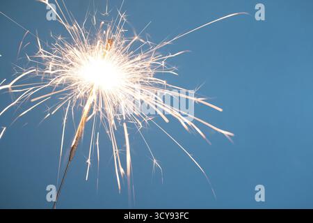 Brennendes bengalisches Weihnachtslicht isoliert auf blauem Hintergrund Stockfoto