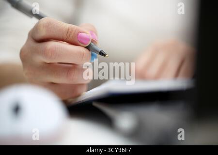 Weibliche Hände mit Schreibfeder auf Notebook Stockfoto