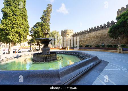 Baku, Aserbaidschan. oktober 2025. Ein Brunnen mit den alten Stadtmauern im Hintergrund im Stadtzentrum Stockfoto