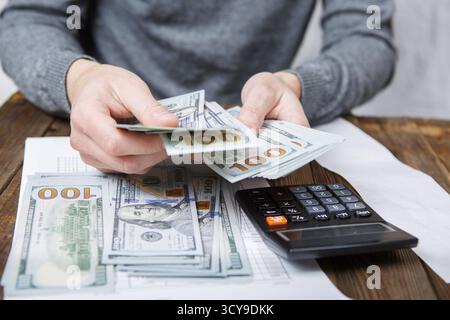 Kaukasische Hände zählen-Dollar-Banknoten auf dunklen Holztisch Stockfoto