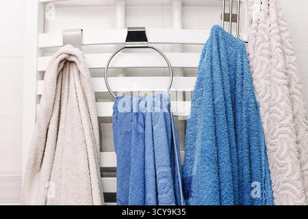 Farbenfrohe Handtücher hängen im Badezimmer. Weiche Stoffe auf Handtuchhalter im Innenbereich. Haushygiene und Sauberkeitskonzept. Gemütliches, tägliches Bad mit Textil Stockfoto