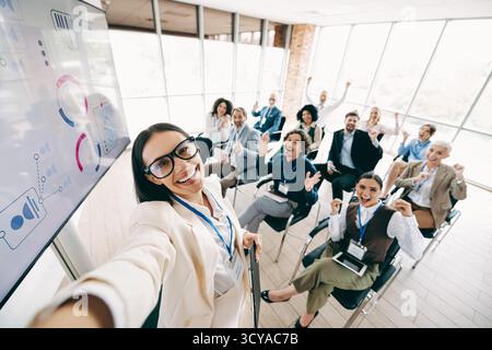 Gruppe von Kollegen, die gemeinsam in einer hellen Büroumgebung anfeuern, während sie an einem Firmenmeeting und einer Schulung teilnehmen Stockfoto