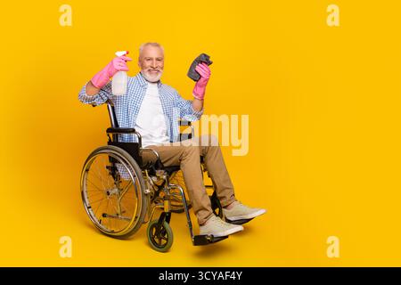 Lustiger Aufräummoment Opa im Rollstuhl sprüht Putzmittel lächelt während der Reha und zeigt Freundlichkeit und Hoffnung für alle Stockfoto