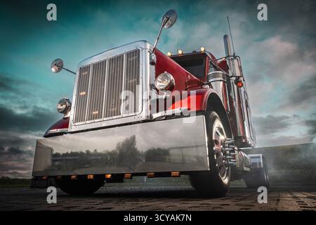 Ein klassischer roter Truck steht geparkt und zeigt seine glänzenden Chromdetails vor einem bewölkten, dramatischen Sonnenuntergang. Stockfoto