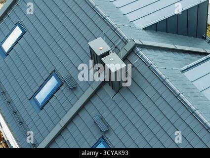 Blick aus der Nähe auf ein modernes Dach mit einzigartigen Lüftungseinheiten und scharfen Winkeln bei hellem Tageslicht. Stockfoto