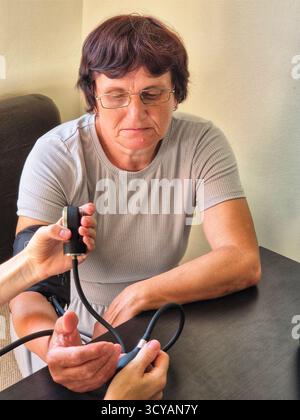 Frau, deren Blutdruck gemessen wird. Gesundheitswesen. Hypertonie. 60-jährige Frau mit Blutdruckmessgerät Stockfoto