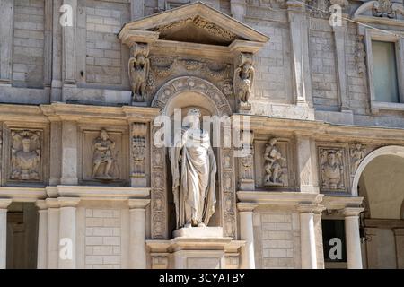Italien, Mailand - 17. Juli 2025: Statue des Heiligen Ambrosius im Palazzo Jureconsulti Piazza Mercanti Piazza Mercanti der alten Mailänder Straße rchitektur. Italienisches Gebäude. Stockfoto