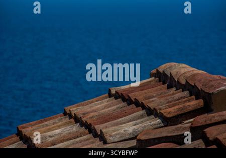 Terrakotta-Dachziegel mit Blick auf das tiefblaue Meer in Monemvasia, Griechenland. Stockfoto