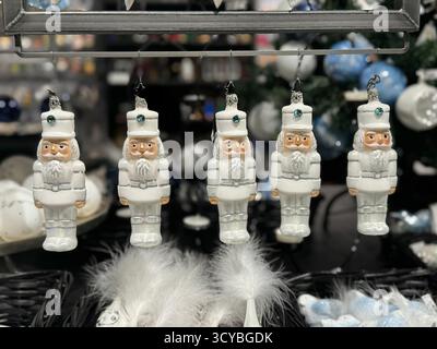 Eine Reihe von Weihnachtsbaumschmuck aus weißem Glas hängt in einem Geschäft Stockfoto