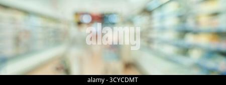 Verschwommener Blick auf einen belebten Supermarktgang mit Einkäufern und Lebensmittelregalen in heller Beleuchtung. Stockfoto