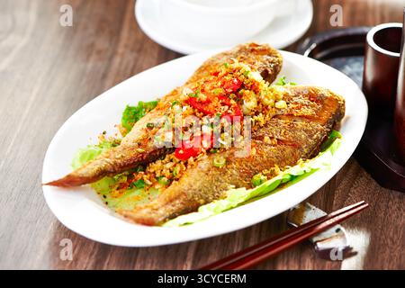 Knuspriges Salz und Pfeffer kleiner gelber Croaker-Fisch mit Stäbchen serviert in einer Schüssel mit klassischem asiatischem Meeresfrüchtegericht Stockfoto