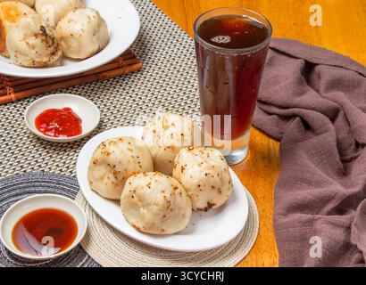 Pfannengebratene Brötchen 4 Stück mit eintauchenden Saucen und einem hohen Glas Eistee isoliert auf Serviette Seitenansicht von taiwan Dim Sum Essen Stockfoto