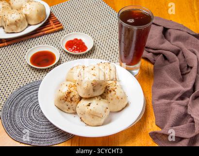 Gebratene Brötchen, 6 Stück mit eintauchenden Saucen und einem hohen Glas Eistee isoliert auf Serviette Seitenansicht von taiwan Dim Sum Food Stockfoto