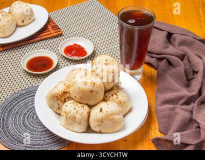 Gebratene Brötchen, 6 Stück mit eintauchenden Saucen und einem hohen Glas Eistee isoliert auf Serviette Seitenansicht von taiwan Dim Sum Food Stockfoto