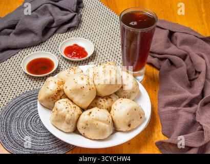 Gebratene Brötchen 10 Stück mit tauchenden Saucen und einem hohen Glas Eistee isoliert auf Serviette Seitenansicht von taiwan Dim Sum Food Stockfoto