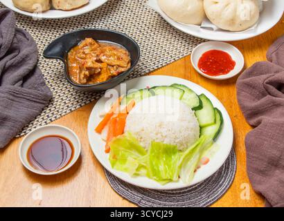 Zitronengras Hühnerreis mit gedämpften Brötchen, Salat und Dipping Sauce serviert in Teller isolierte Serviette Seitenansicht chinesischer Dim Sum-Speisen Stockfoto