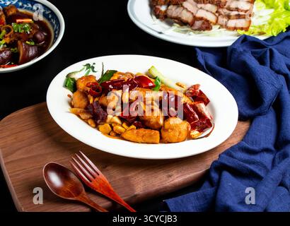 Kung Pao Huhn mit Löffel und Gabel serviert in Schüssel isoliert auf Holzbrett Seitenansicht von taiwanischem Essen Stockfoto
