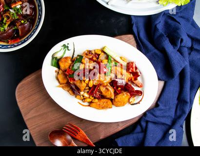 Kung Pao Huhn mit Löffel und Gabel serviert in einer Schüssel isoliert auf Holzbrett mit Blick auf taiwanisches Essen Stockfoto