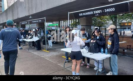 Toronto, ON, Kanada - 18. Oktober 2025: Läufer holen ihre Startnummern von Freiwilligen an einem Outdoor-Registrierungstisch vor der Veranstaltung ab. Stockfoto