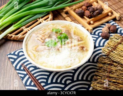 Gebratene Entenfleischsuppe mit Reisnudeln mit Frühlingszwiebeln, Löffel und Essstäbchen in Schüssel isoliert auf Serviette Seitenansicht auf Tisch taiwan Essen Stockfoto