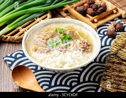 Gebratenes Entenfleisch mit Reis mit Frühlingszwiebeln, Löffel und Essstäbchen in Schüssel isoliert auf Serviette Seitenansicht auf dem Tisch taiwan Essen Stockfoto