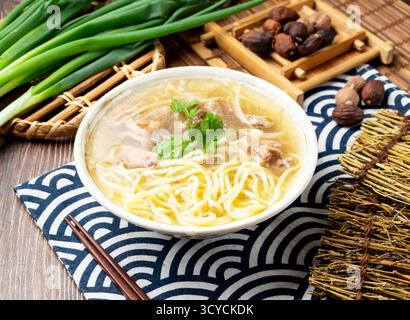 Gebratene Entennudeln Suppe mit Frühlingszwiebeln, Löffel und Essstäbchen in Schüssel isoliert auf Serviette Seitenansicht auf Tisch taiwan Essen Stockfoto