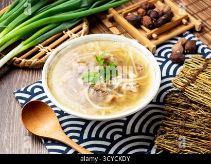 Gebratene Entensuppe mit Nudeln Frühlingszwiebeln, Löffel und Essstäbchen in Schüssel isoliert auf Serviette Seitenansicht auf Tisch taiwan Essen Stockfoto
