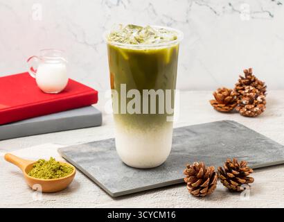 Ice Green Tea Latte serviert in Einwegglas, isoliert an Bord, Seitenansicht des taiwanesischen Eisgetränks Stockfoto