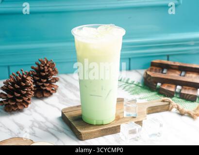 Iced Mint Milk Tea mit Eiswürfel in hohem Glas serviert auf einem Holzbrett, Seitenansicht auf taiwan kaltes Getränk Stockfoto