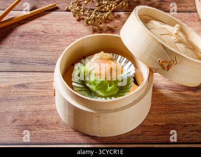 Garnelen Siew Mai gedämpfte Garnelenknödel in Bambusdampfer mit Stäbchen isoliert auf Holztisch Seitenansicht von Dim Sum taiwan Essen Stockfoto