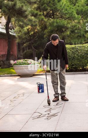 Peking, China - 5. Oktober 2018: Bodenkalligraphie, Malerei mit Wasser, auf dem Boden in China ist eine beliebte und alte Praxis. Stockfoto