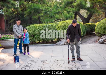Peking, China - 5. Oktober 2018: Bodenkalligraphie, Malerei mit Wasser, auf dem Boden in China ist eine beliebte und alte Praxis. Stockfoto