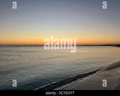 Sonnenuntergang über ruhigen mediterranen Gewässern mit sanften Wellen und pastellfarbenem Himmel, der an der ägyptischen Küste Frieden und Gelassenheit beschwört. Stockfoto