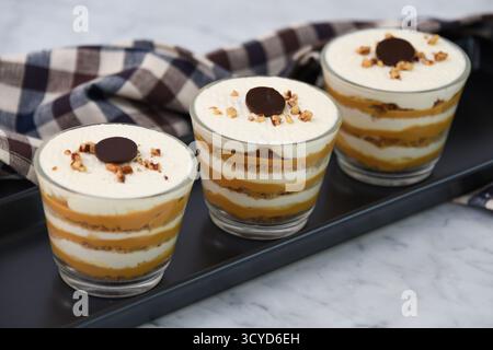 Klassisches Tiramisu-Dessert in Gläsern mit Serviette, die Schichten von Kaffee getränkt, cremiger Mascarpone und staubtem Kakao mit Schlagsahne zeigt, und Stockfoto