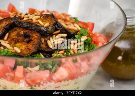 Frischer mediterraner Couscous-Salat mit gegrillter Aubergine mit Couscous, Tomaten, Petersilie, gegrillten Auberginen-Scheiben und gerösteten Pinienkernen mit bo Stockfoto