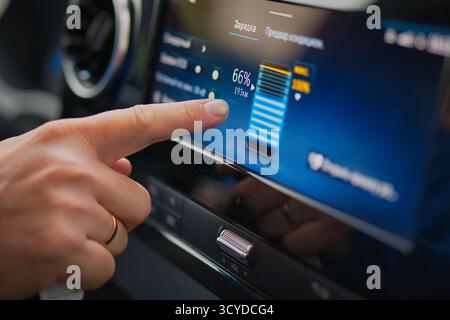 Ladeanzeige für Elektroautos mit Touchscreen, der den Batteriestand und die Reichweite im modernen Fahrzeuginnenraum anzeigt Stockfoto