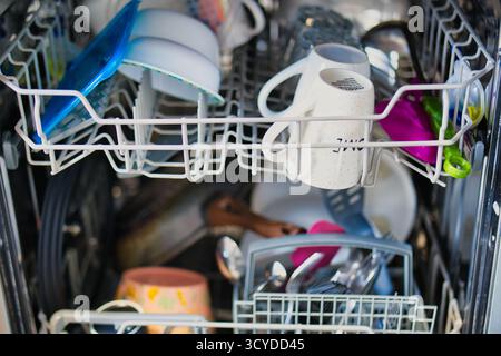 Innenansicht eines beladenen Geschirrspülers mit verschiedenen Geschirr, Utensilien und Kochgeschirr, bereit für den Reinigungszyklus Stockfoto