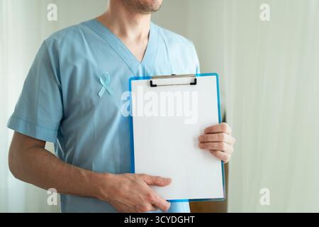Nahaufnahme eines männlichen Arztes mit medizinischer Uniform mit blauem Satinband. November Prostatakrebs Awareness Monatskonzept, Prävention, Früherkennung und onkologische Behandlung. Stockfoto