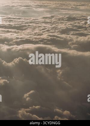 Goldenes Sonnenuntergangslicht, das Strahlen über dicken, geschichteten Wolken wirft und eine traumhafte Aussicht aus der Luft schafft, perfekt für Reisen, ruhige Inspiration, ruhige Sicht aus der Luft Stockfoto