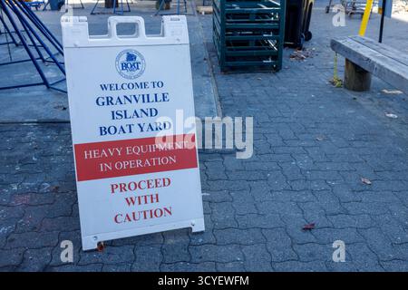 Vancouver, Kanada - Oktober 6,2025: Weißes Sandwichschild, das vor dem Betrieb schwerer Maschinen am Granville Island Boat Yard warnt Stockfoto